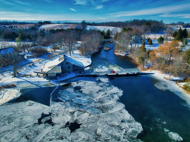 Aerial view of the river and historic mill in winter